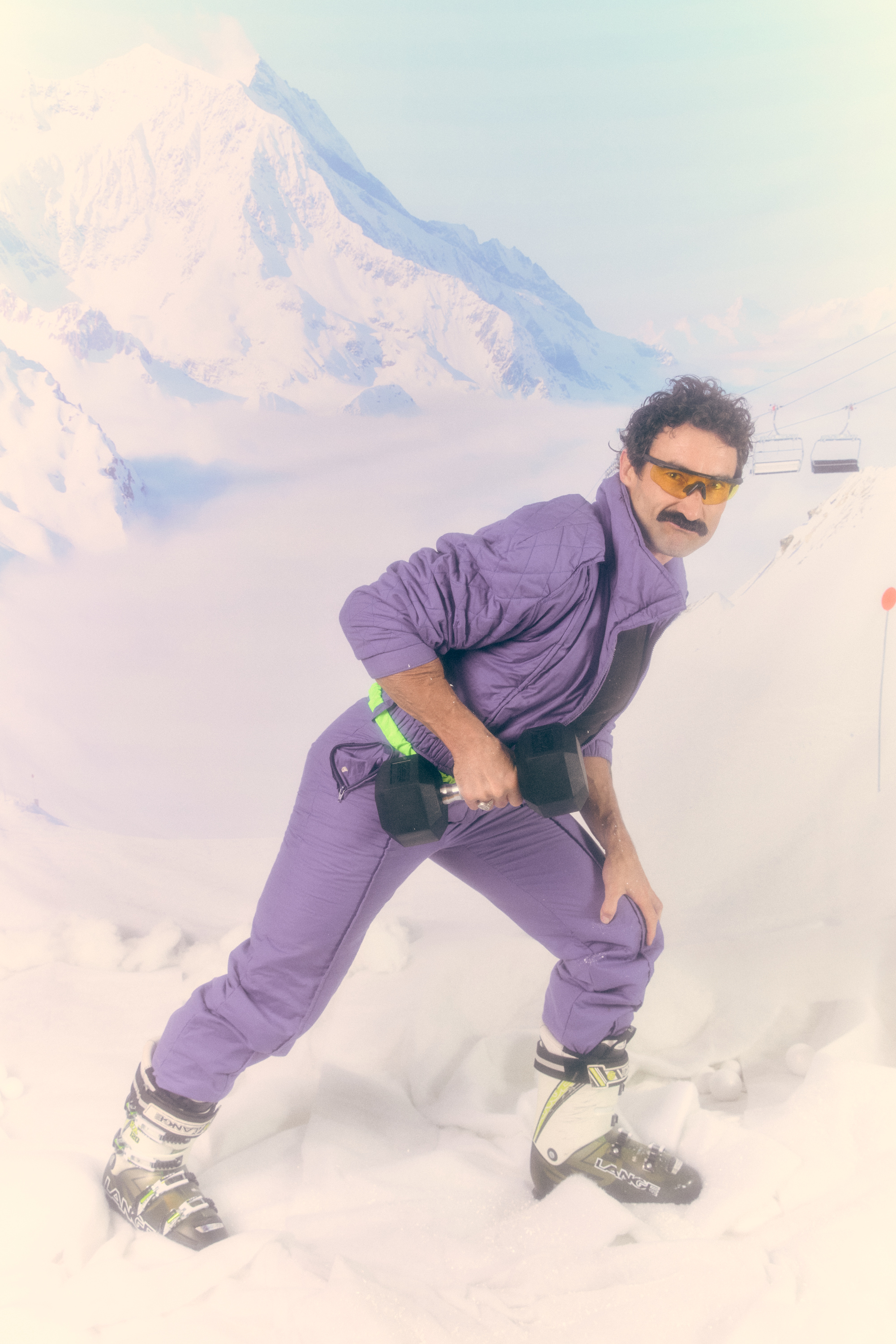 Limber crew member in a purple ski suit striking a pose on the mountain
