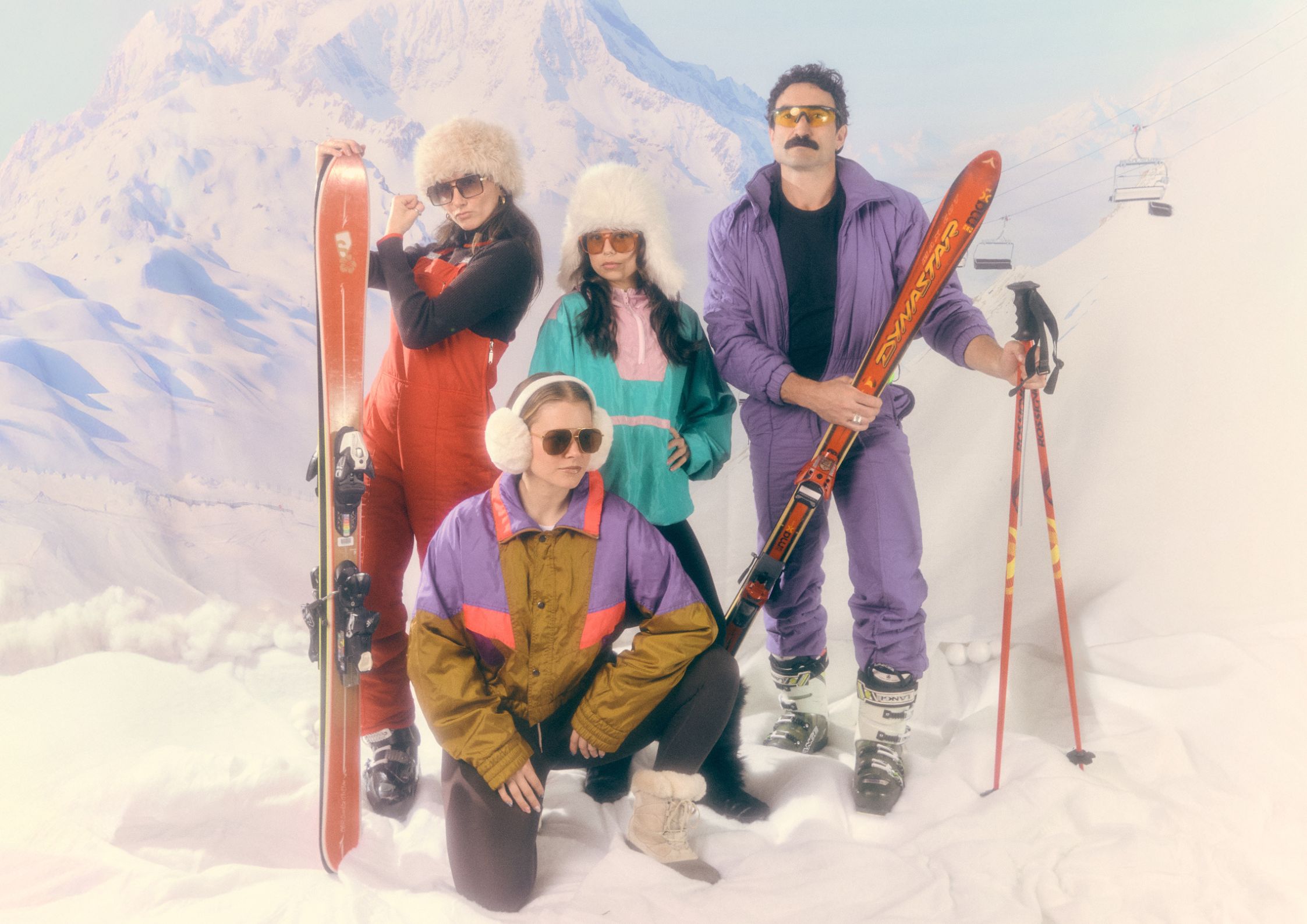 Four Limber crew members in full 80s ski gear, posed in front of a snowy mountain backdrop